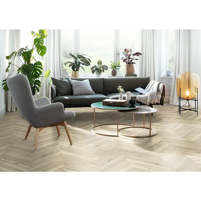 Egger Laminat NatureSense - Rillington Eiche hell, Fischgrät, 1.292 x 327 x 8 mm - Ein Wohnzimmer mit einem grauen Sofa, einem Sessel, Couchtischen und einem Teppich mit Fischgrätmuster.