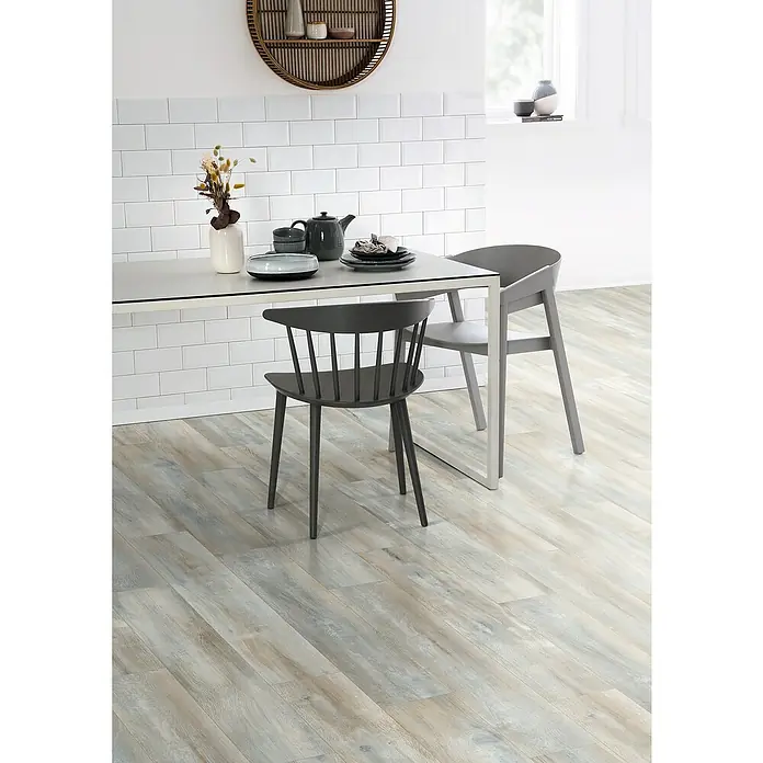 Egger Laminat NatureSense - Abergele Eiche dunkel, Landhausdiele, 1.292 x 193 x 8 mm - Helles Interieur mit einem Esstisch mit Geschirr, zwei Stühlen und einem runden Wandregal an einer weißen gefliesten Wand.