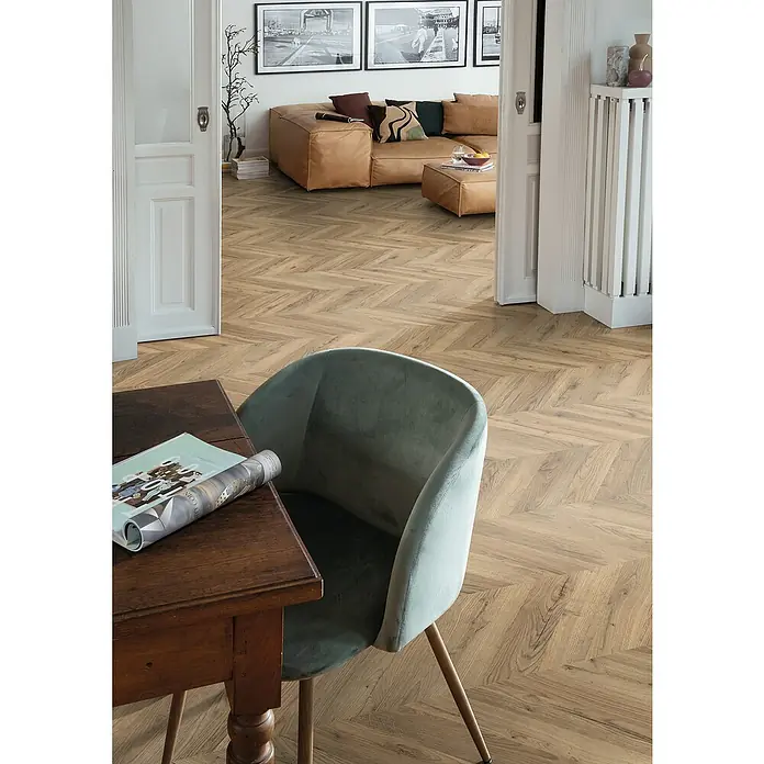 Egger Laminat NatureSense - Rillington Eiche dunkel, Fischgrät, 1.292 x 327 x 8 mm - Elegantes Esszimmer mit einem Holztisch, einem mintgrünen Stuhl und einem stilvollen Bodenbelag in Fischgrätmuster.