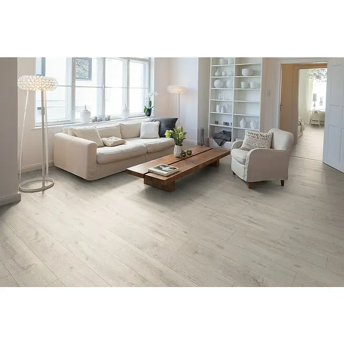 Egger Laminat NatureSense Aqua - Eiche Sedan, Landhausdiele, 1.292 x 193 x 10 mm - Wohnzimmer mit hellem Holzboden, Sofa, Sessel und Bücherregal. Die hellen Dielen verleihen dem Raum eine freundliche Atmosphäre.