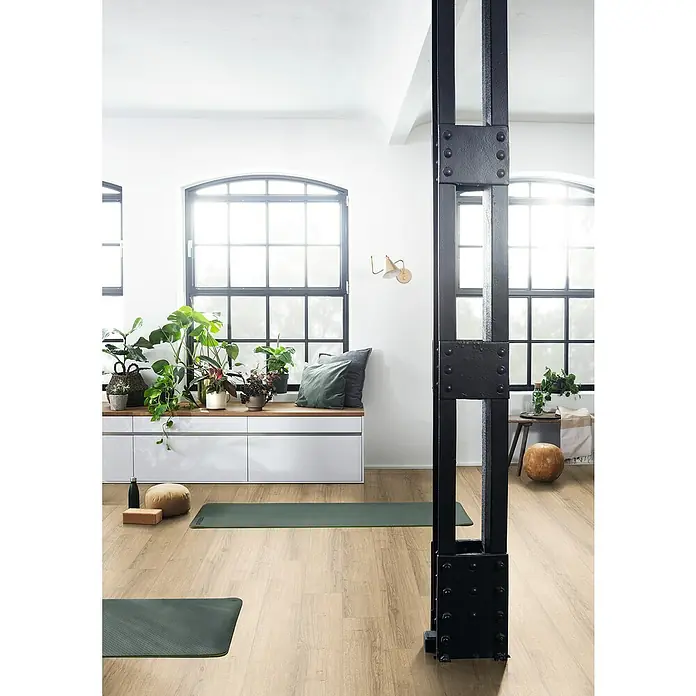 Egger Laminat NatureSense Aqua - Sherman Eiche hellbraun, Landhausdiele, 1.292 x 193 x 10 mm - Heller Raum mit Yogamatten und Pflanzen vor den Fenstern. Der Fokus liegt auf den grünen Yogamatten und den Pflanzen.