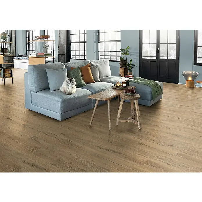 Egger Laminat NatureSense Aqua - Melba Eiche natur, Landhausdiele, 1.292 x 193 x 10 mm - Geräumiges Wohnzimmer mit stilvollem Sofa, Holztisch und einem bezaubernden Perserkatze, der dem Raum einen Hauch von Eleganz verleiht.