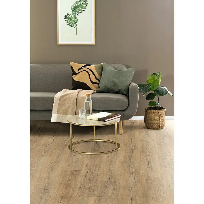 Egger Laminat NatureSense Aqua - Melba Eiche natur, Landhausdiele, 1.292 x 193 x 10 mm - Wohnzimmer-Szene mit grauem Sofa, Zierkissen, Tisch mit Getränken und Pflanze im Korb auf Holzboden.
