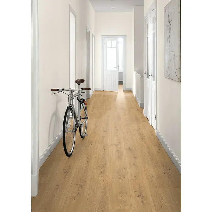 Egger Laminat NatureSense Aqua - Predaia Eiche honig, Landhausdiele, 1.292 x 193 x 8 mm - Ein langer Flur mit hellem Holzboden ist mit einem Fahrrad und weißen Türen ausgestattet. Kunst hängt an der Wand und die Wände sind hell.
