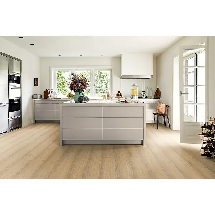 Egger Laminat NatureSense Aqua - Sherman Eiche honig, Landhausdiele, 1.292 x 246 x 8 mm - Helles Küchendesign mit einer modernen Kücheninsel in Grau, ergänzt durch Edelstahlgeräte und viel Tageslicht für eine freundliche Atmosphäre.