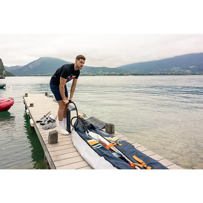 Sevylor Kajak Maui 2 + 1 - L x B: 380 x 98 cm, Nutzlast: 250 kg, Geeignet für: 2+1 Personen - Ein Mann pumpt ein aufblasbares Kajak auf einem hölzernen Steg am See auf, bereit für ein Paddel-Abenteuer mit dem Boot.