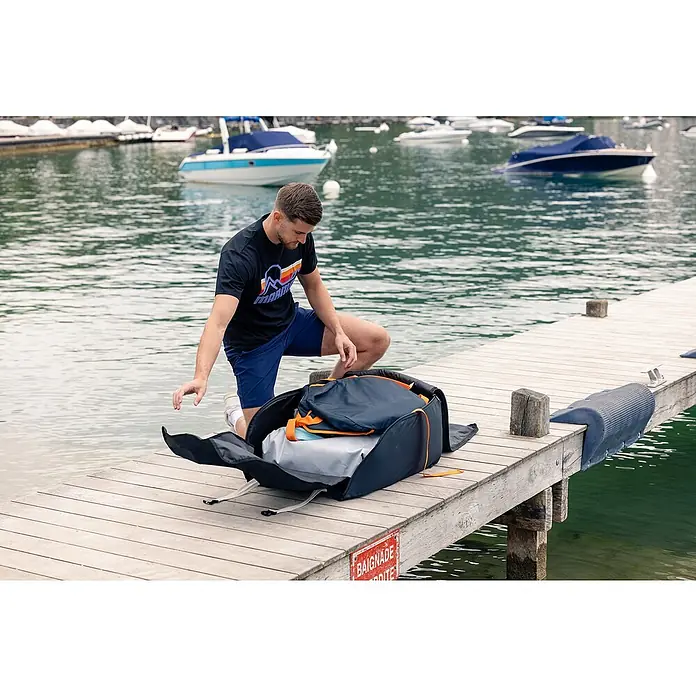 Sevylor Kajak Colorado Kit - L x B: 342 x 96 cm, Nutzlast: 180 kg, Geeignet für: 2 Personen - Mann kniet auf einem Steg mit geöffneter Reisetasche. Die Tasche ist ideal für Reisen und bietet viel Platz für Kleidung und andere Gegenstände.