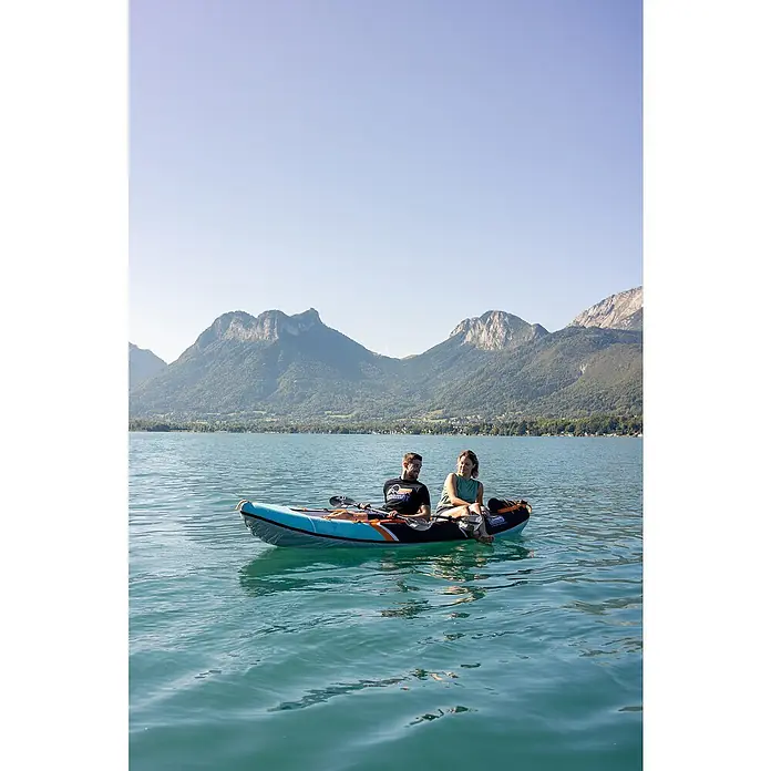 Sevylor Kajak Colorado Kit - L x B: 342 x 96 cm, Nutzlast: 180 kg, Geeignet für: 2 Personen - Ein türkisfarbenes und schwarzes aufblasbares Kajak liegt auf einem See vor einer Bergkulisse, auf dem zwei Personen sitzen und die Landschaft genießen.