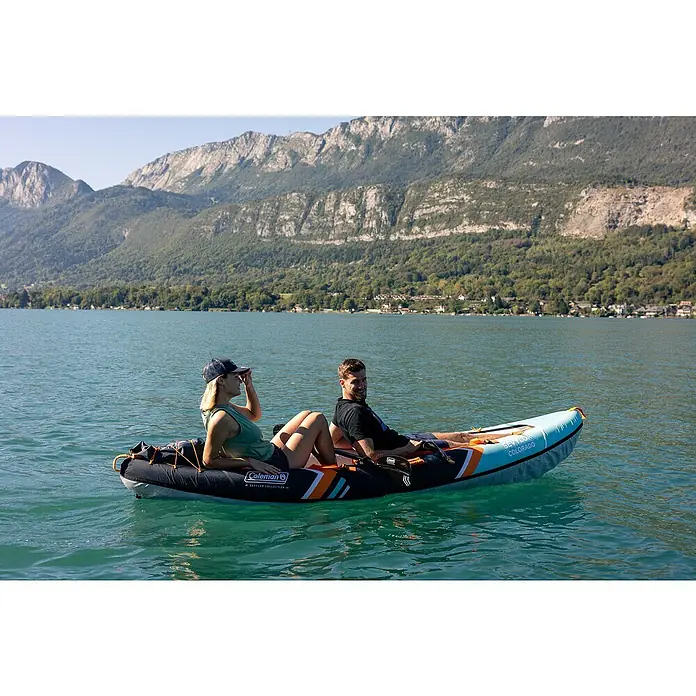 Sevylor Kajak Colorado Kit - L x B: 342 x 96 cm, Nutzlast: 180 kg, Geeignet für: 2 Personen - Ein Coleman Kajak auf einem See mit zwei Personen an Bord, vor einer Bergkulisse. Ideal für entspannte Paddeltouren auf dem Wasser.