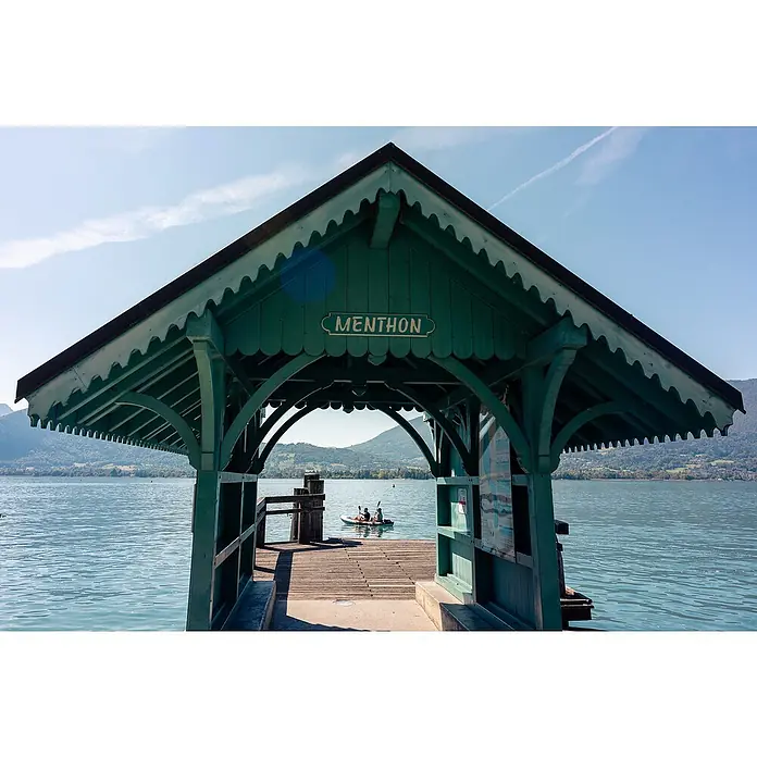 Sevylor Kajak Colorado Kit - L x B: 342 x 96 cm, Nutzlast: 180 kg, Geeignet für: 2 Personen - Blick durch den grünen Unterstand am See mit dem Schriftzug "MENTHON", der friedliche Momente am Wasser einfängt.