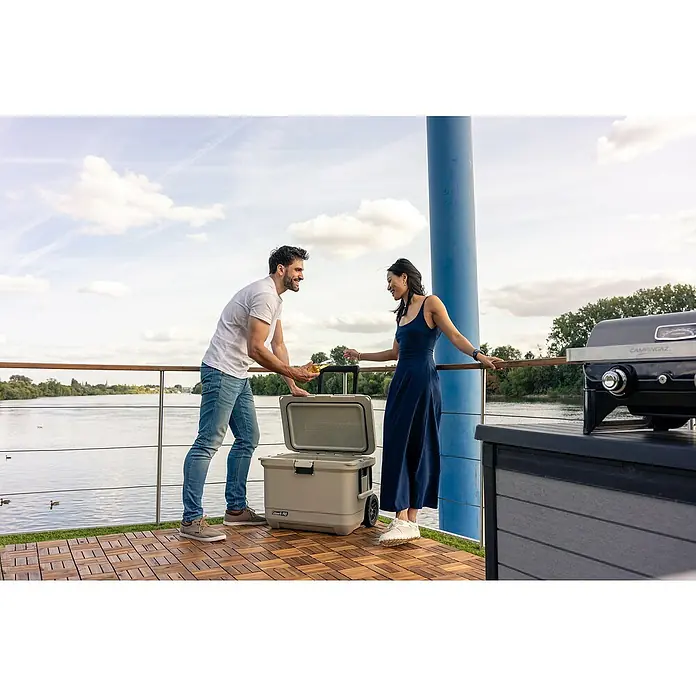 Coleman Kühlbox Pro 55QT - L x B x H: 65 x 37 x 48 cm, Schwarz, 52 l - Bild von einem Coleman Kühlbox, die von einem Mann und einer Frau an einem sonnigen Tag im Freien benutzt wird.