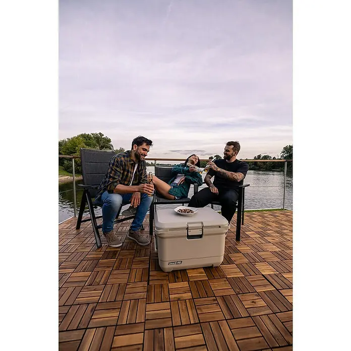 Coleman Kühlbox Pro 45QT - L x B x H: 26 x 47 x 43 cm, Schwarz, 42,5 l - Drei Freunde entspannen mit Getränken neben einem Coleman Pro Kühlbox auf einem Holzdeck. Die Kühlbox hält die Getränke kühl.