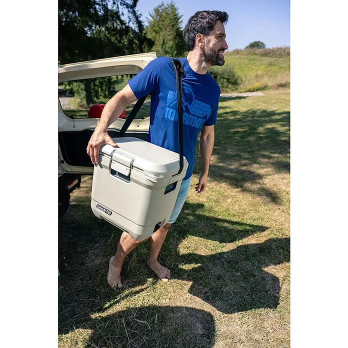 Coleman Kühlbox Pro 25QT - L x B x H: 35 x 45 x 45 cm, Weiß, 24 l - Ein Mann trägt eine Coleman Pro Kühlbox mit einem Tragegurt über der Schulter. Ideal für Campingausflüge und Outdoor-Abenteuer.