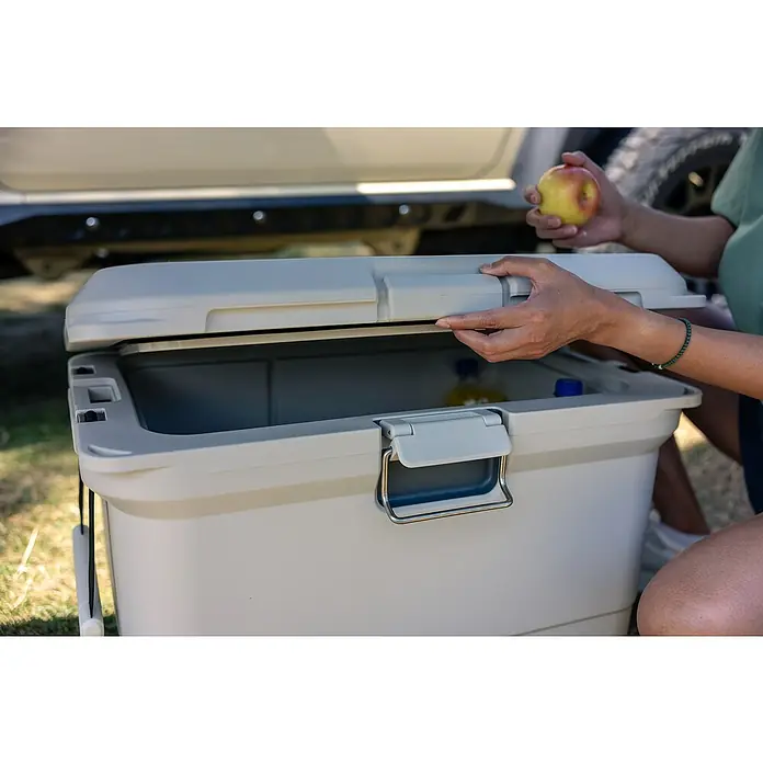Coleman Kühlbox Pro 45QT - L x B x H: 26 x 47 x 43 cm, Schwarz, 42,5 l - Person öffnet einen Kühlbehälter, um eine Erfrischung zu entnehmen, während sie einen Apfel hält.