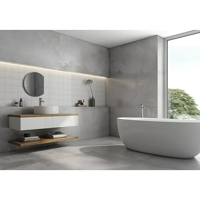 BHS Showroom Pavimento porcelánico Iron Slim - 80 x 160 cm, Gris, Satinado, Rectificado - Un baño moderno con una bañera exenta, un lavabo elegante y azulejos grises que crean un ambiente sereno y contemporáneo.