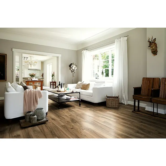 Egger Laminat NatureSense Aqua - Perganti Nussbaum braun, Landhausdiele, 1.292 x 193 x 8 mm - Elegantes Wohnzimmer mit warmem Holzboden, der eine einladende Atmosphäre schafft. Der Boden harmoniert perfekt mit den weißen Möbeln und dem natürlichen Licht.