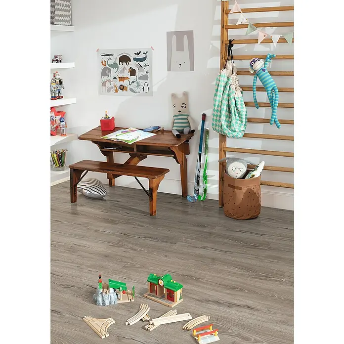 Egger Laminat Aquadura+ - Panora Eiche grau, Landhausdiele, 1.292 x 193 x 7,5 mm - Kinderzimmer mit Holztisch, Spielzeug und Wanddekorationen. Der graue Holzboden verleiht dem Raum eine warme Atmosphäre.