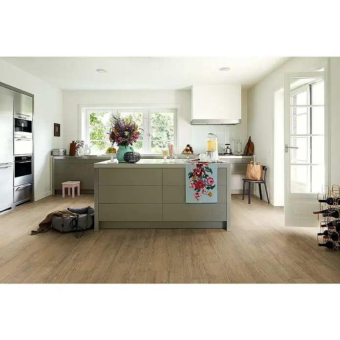 Egger Laminat Aquadura+ - Elva Eiche braun, Landhausdiele, 1.292 x 193 x 7,5 mm - Helle Küche mit Mittelinsel, Blumenarrangement und stilvollem Weinständer für eine einladende Atmosphäre.