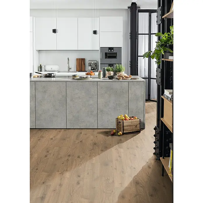 Egger Laminat Aquadura+ - Almington Eiche natur, Landhausdiele, 1.292 x 193 x 7,5 mm - Kücheninsel mit Betonfronten und Holzboden mit einem Holzkiste voller Äpfel darauf.