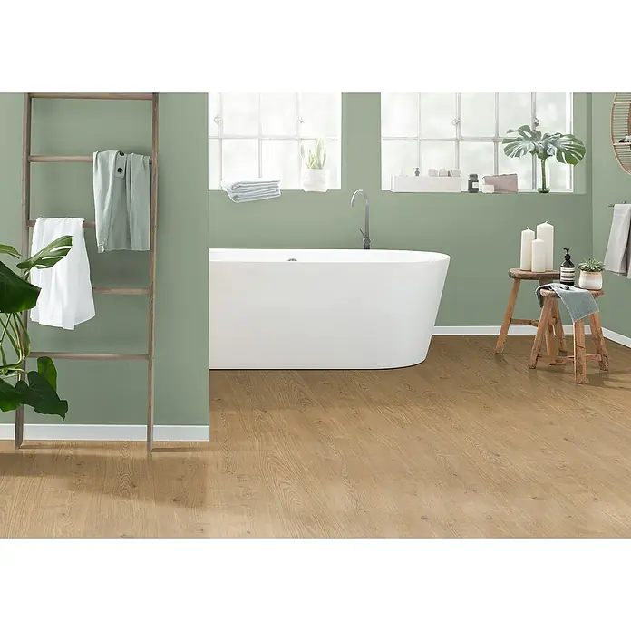Egger Laminat Aquadura+ - Berdal Eiche natur, Landhausdiele, 1.292 x 193 x 7,5 mm - Badezimmer mit freistehender Badewanne, Holzleiter mit Handtüchern und Holzboden, der eine warme und natürliche Atmosphäre schafft.