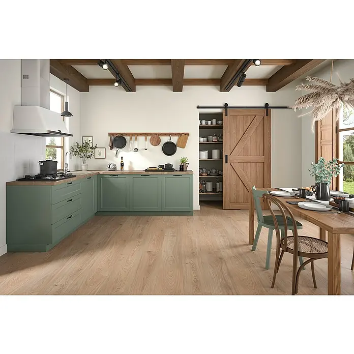 Egger Laminat Aquadura+ - Lana Eiche natur, Landhausdiele, 1.292 x 246 x 7,5 mm - Geräumige Landhausküche mit grünen Schränken, Holzbalkendecke und einem grossen Holzesstisch. Die Küche ist hell und einladend.