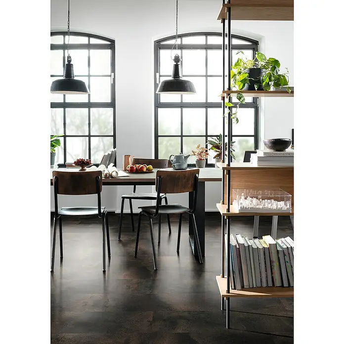 Egger Laminat Aquadura+ - Titanit anthrazit, 1.292 x 327 x 7,5 mm - Esszimmer mit Holzboden, Esstisch mit Stühlen, zwei Pendelleuchten und einem offenen Bücherregal, das mit Pflanzen und Büchern dekoriert ist.