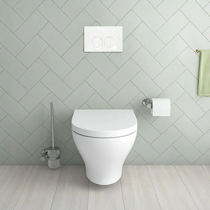 Geberit Betätigungsplatte Delta - 115.125.11.5 - Weiß - Eine moderne Toilette in Weiß vor einer hellen, gemusterten Wand, inklusive Spülknopf, Toilettenpapierhalter und Bürste.