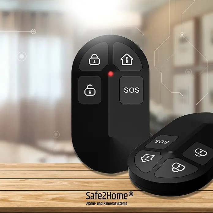 Safe2Home Alarmanlagen-Set Profi Serie SP310 - 9 -tlg., L x B x H: 195 x 136 x 31 mm - Zwei schwarze Safe2Home® Alarmanlagen-Fernbedienungen auf einem Holztisch mit den Aufschriften "SOS" und Schlosssymbolen.