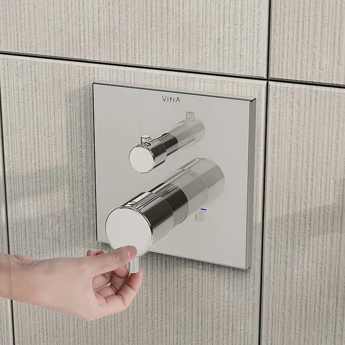 VitrA Flow Square UP-Badewannenarmatur - Ausladung Armatur: 91 mm, Chrom, Glänzend - Verchromter VitrA-Duschmischer an einer gefliesten Wand, eine Hand reguliert den unteren Regler.