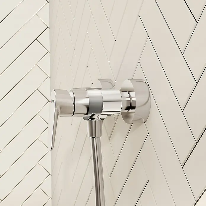 VitrA Flow Soft Brausearmatur - Ausladung: 12,7 cm, Chom, Glänzend - Verchromte Duscharmatur mit Einhebelmischer und angeschlossenem flexiblem Schlauch, an einer weißen Fischgrät-Fliesenwand montiert.