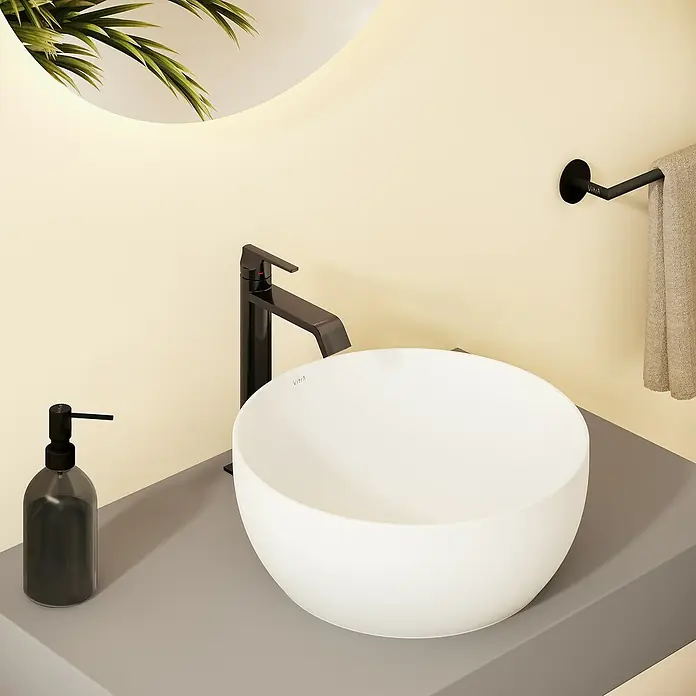 VitrA Suit Waschtischarmatur - Schwarz, Glänzend, Höhe: 26,4 cm - Weißes Aufsatzwaschbecken mit schwarzem Wasserhahn und Seifenspender auf grauer Arbeitsplatte in modernem Bad.