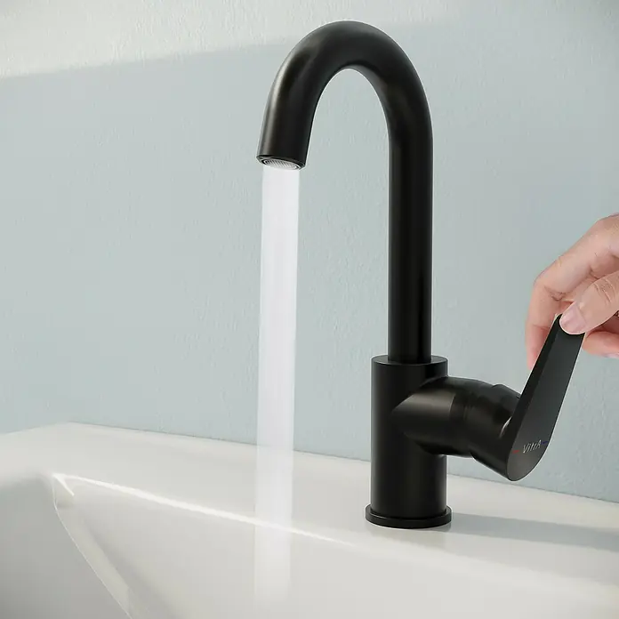 VitrA Flow Square Waschtischarmatur - Schwarz, Matt, Höhe: 28 cm - Mattschwarzer VitrA Wasserhahn mit laufendem Wasser im weißen Waschbecken. Eine Hand betätigt den Hebel.