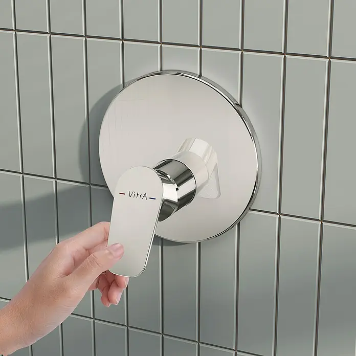 VitrA Flow Soft Brausearmatur - Chrom, Glänzend, Ausladung Armatur: 88 mm, Ohne Hülse - Hand verstellt eine VitrA Chrom-Duscharmatur an einer Fliesenwand.