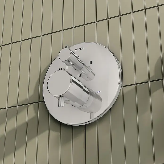 VitrA Flow Soft UP-Badewannenarmatur - Chrom, Glänzend, Ausladung Armatur: 88 mm, Inclusive Hülse - Verchromte thermostatische Duscharmatur mit zwei Griffen und VitrA-Logo, montiert auf beigen vertikalen Fliesen.