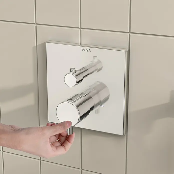 VitrA Flow Square UP-Badewannenarmatur - Ausladung Armatur: 89 mm, Chrom, Glänzend - VitrA Brausethermostat aus poliertem Chrom an einer gefliesten Wand; eine Hand verstellt den unteren Griff.
