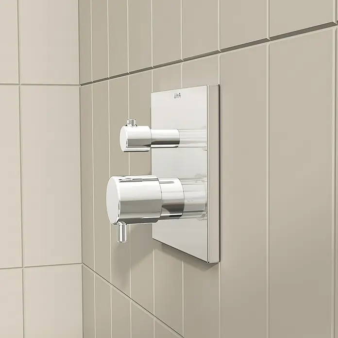 VitrA Flow Square UP-Badewannenarmatur - Ausladung Armatur: 89 mm, Chrom, Glänzend - Verchromte Duscharmatur mit zwei zylindrischen Griffen, eine mit Umsteller, bündig in eine beige Fliesenwand montiert.