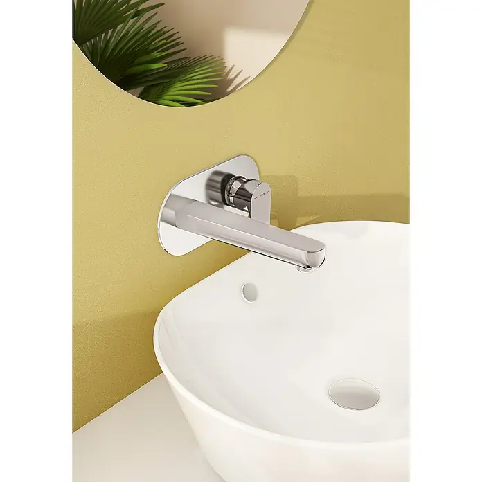 VitrA Flow Soft Waschtischarmatur - Chrom, Glänzend, Ausladung Armatur: 200 mm - Verchromte Wandarmatur über einem weißen Aufsatzwaschbecken vor einer gelben strukturierten Wand.