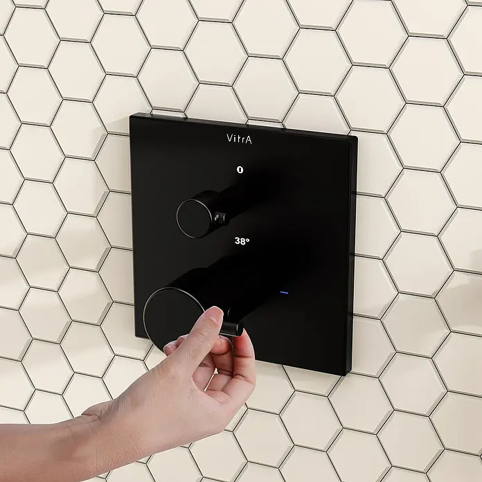 VitrA Flow Square UP-Badewannenarmatur - Ausladung Armatur: 91 mm, Schwarz, Matt - Eine Hand verstellt eine schwarze quadratische Duscharmatur mit zwei runden Bedienelementen und Digitalanzeige für 38 Grad.
