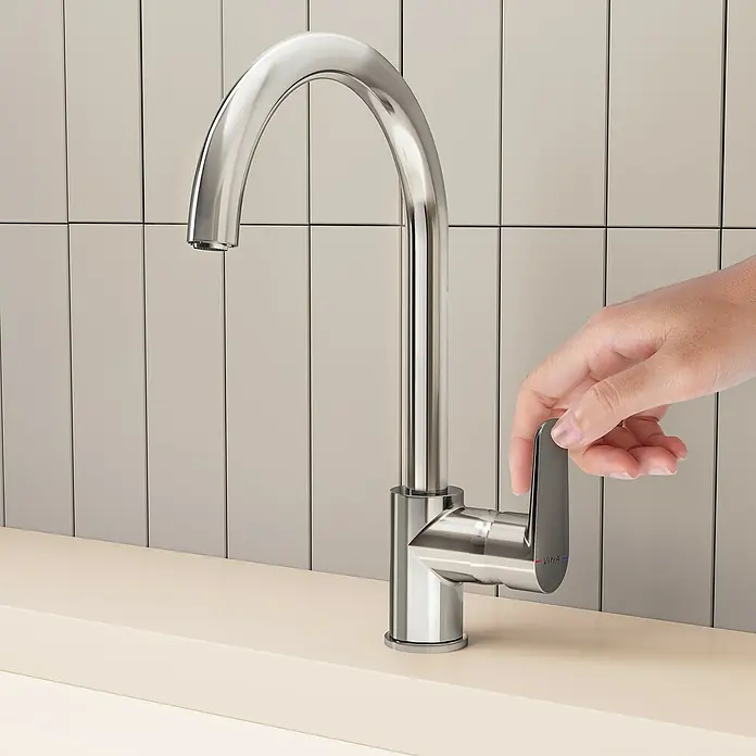 VitrA Flow Soft Spültischarmatur - Fester Auslauf, Chrom, Glänzend, Höhe: 35,2 cm - Eine Hand bedient eine Küchenarmatur aus Chrom auf einer hellen Arbeitsplatte.