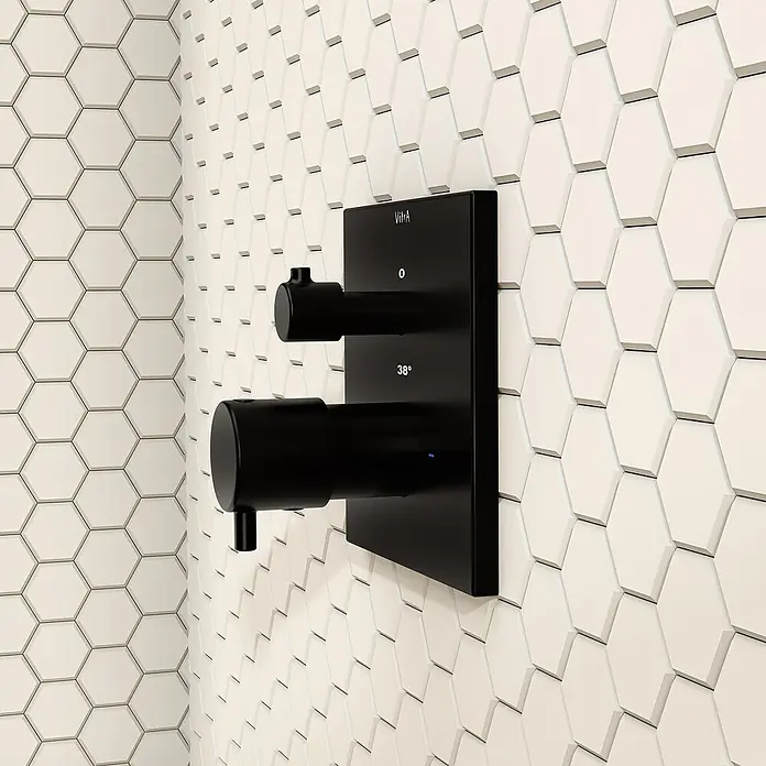 VitrA Flow Square UP-Badewannenarmatur - Ausladung Armatur: 91 mm, Schwarz, Matt - Mattschwarzer Duschthermostat mit zwei Griffen und digitaler 38°C Anzeige, montiert auf cremefarbenen Sechseckfliesen.