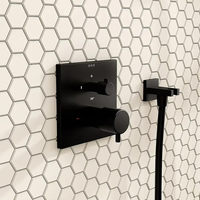 VitrA Flow Square UP-Badewannenarmatur - Ausladung Armatur: 91 mm, Schwarz, Matt - Mattschwarze Duscharmatur und Schlauchhalter an einer Wand mit beigefarbenen sechseckigen Fliesen.