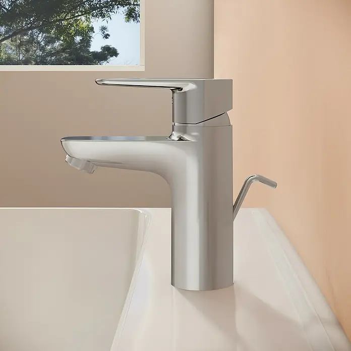 VitrA Flow Soft Waschtischarmatur - Chrom, Höhe: 15 cm, Mit Zugstange - Moderner, silberfarbener Wasserhahn mit Einhebelmischer und Ablaufgarnitur auf einem weißen Waschbecken.