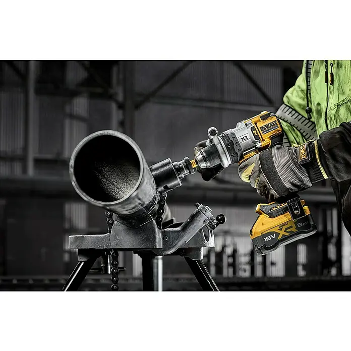 DeWalt XR 18V Taladro atornillador percutor de batería DCD1007W -  - Primer plano de un taladro Dewalt perforando un tubo de metal, con soporte para tubos, y una persona en ropa de trabajo.