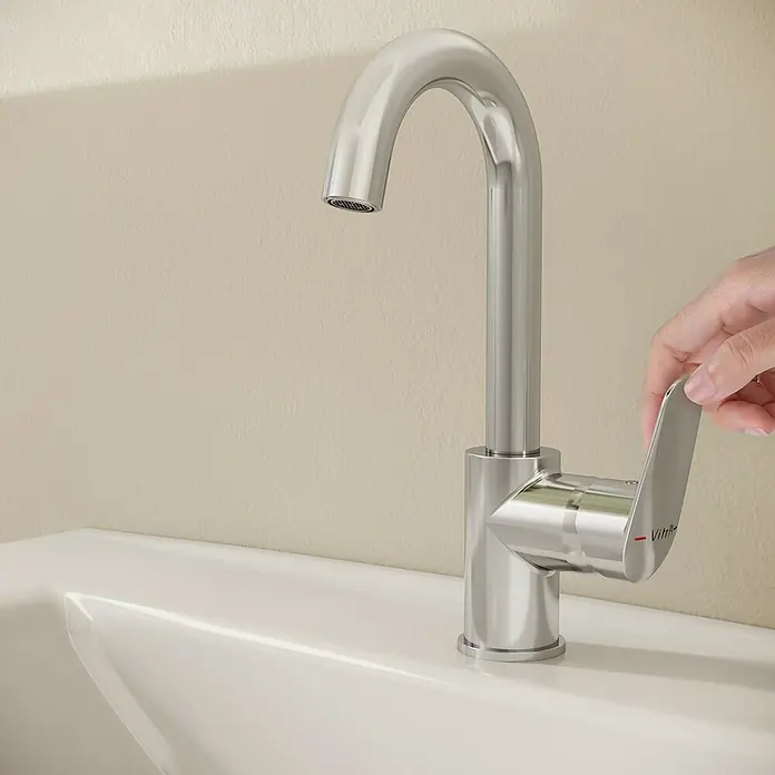 VitrA Flow Round Waschtischarmatur - Höhe: 28 cm, Ausladung Armatur: 114 mm, Chrom - Eine Hand betätigt den Hebel einer modernen Chromarmatur auf einem weißen Waschbecken.