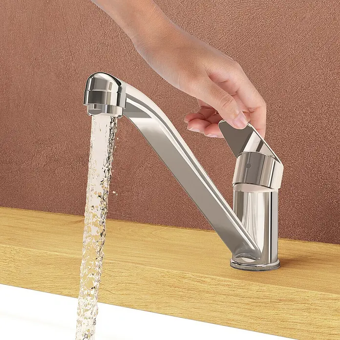 VitrA Flow Round Spültischarmatur - Höhe: 17,4 cm, Chrom, Glänzend - Hand dreht silberfarbenen Wasserhahn auf, aus dem Wasser fließt, auf Holz montiert.