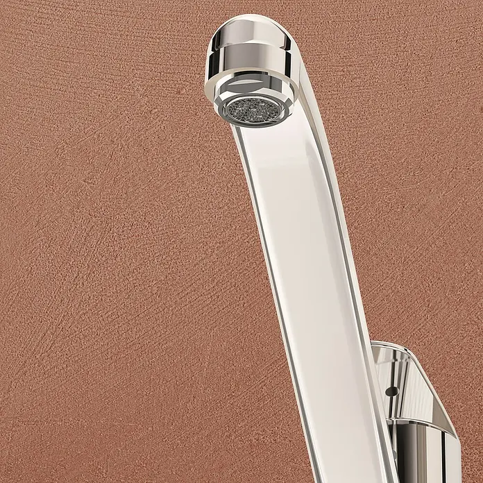 VitrA Flow Round Spültischarmatur - Höhe: 17,4 cm, Chrom, Glänzend - Glänzender Chrom-Wasserhahn in modernem Design, montiert an einer strukturierten rotbraunen Wand.