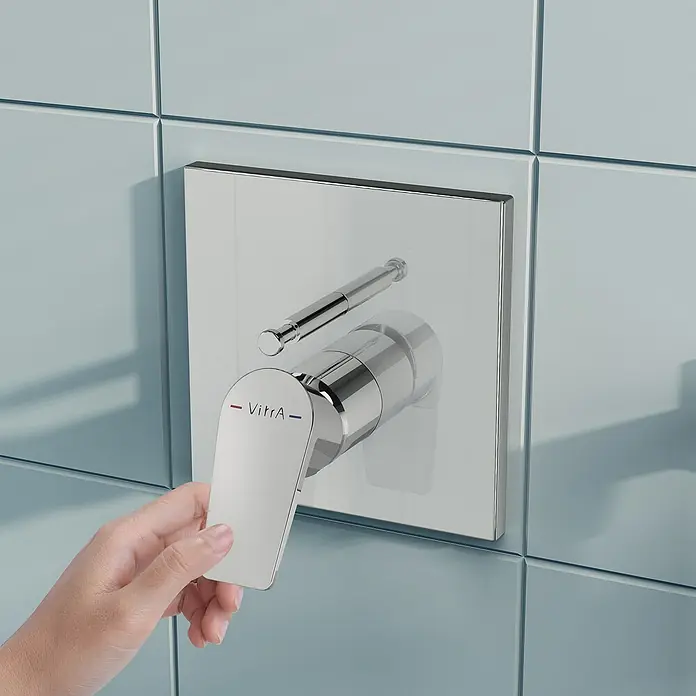 VitrA Flow Square UP-Badewannenarmatur - Ausladung Armatur: 90 mm, Chrom, Glänzend - Hand verstellt einen verchromten VitrA Duschmischer an einer gefliesten Wand.