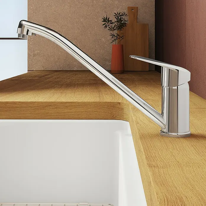 VitrA Flow Round Spültischarmatur - Höhe: 17,4 cm, Chrom, Glänzend - Chrom-Küchenarmatur auf einer hellen Holz-Arbeitsplatte neben einem weißen Spülbecken.