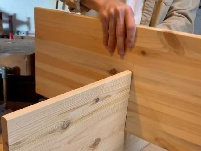 2 Holzplatten werden ineinander gesteckt, damit ein X entsteht