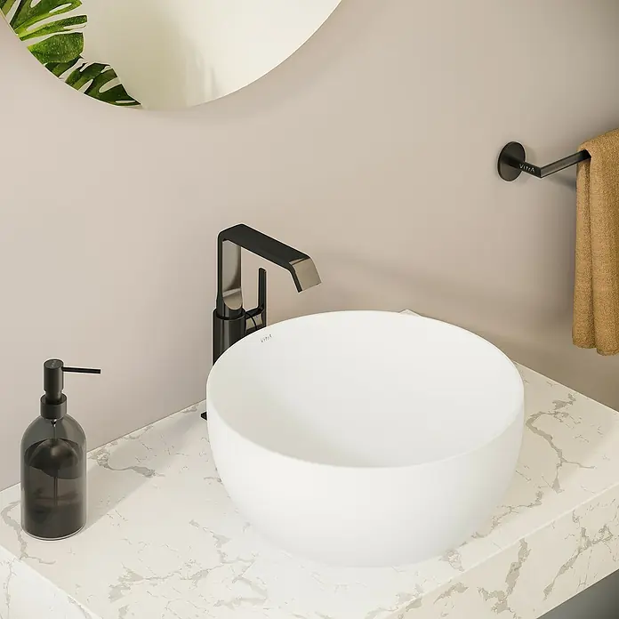 VitrA Suit Waschtischarmatur - Schwarz, Glänzend, Ohne Zugstange, Höhe: 25,7 cm - Weißes Aufsatzwaschbecken, schwarze Armatur und schwarzer Seifenspender auf einer Marmor-Arbeitsplatte in einem modernen Badezimmer.